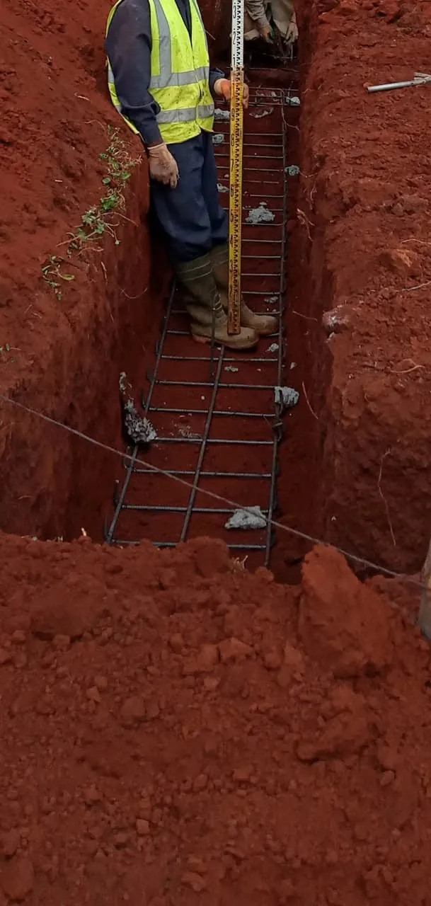 Foundation trench: Rebar cage checked with a levelling staff before concrete.